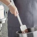 A person using a Choice white spoonula to mix chocolate in a bowl.