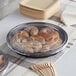 A Choice plastic catering tray with food in it and wooden forks on a table.