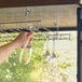 A hand holding wine glasses over a Regency chrome wire bar glass rack.