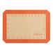 An orange Baker's Lane silicone baking mat with ruler indices.