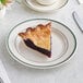 An Acopa ivory stoneware plate with green bands holding a slice of pie.