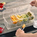 A person holding a Tablecraft condiment bar with fruit and drinks.