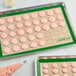 A Baker's Lane green silicone mat with macarons on it.