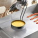A person using a Vigor egg ring to cook bacon on a pan.