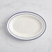 An ivory Acopa stoneware oval platter with blue lines on the rim.