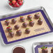 A Baker's Lane purple silicone baking mat with chocolate covered strawberries on it.