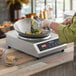 A person using a Galaxy countertop induction wok to cook food.