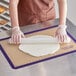 A woman rolling out dough on a purple Baker's Lane silicone baking mat.