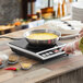A woman using a Galaxy countertop induction range to cook eggs in a pan.