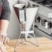 A woman using a Choice stainless steel confectionery dispenser funnel to fill a pastry.