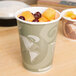 A bowl of fruit and a bowl of food on a counter with a Eco-Products Evolution World soup cup of fruit