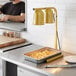 A man using an Avantco countertop heat lamp to cook food in a professional kitchen.
