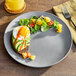 An American Metalcraft matte grey round coupe melamine plate with a salad and toast on it.