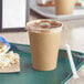 A tray with a brown Kraft paper cold cup filled with a brown beverage.