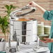 A woman using an Acopa Manchester stainless steel chafer to serve soup at an outdoor catering event.