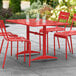 A Lancaster Table & Seating red powder-coated aluminum table with chairs on an outdoor patio.