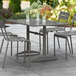 A Lancaster Table & Seating gray outdoor dining table with a drink on it.