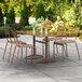 A brown Lancaster Table & Seating outdoor table with chairs on a patio.