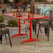 A rectangular red powder-coated aluminum outdoor dining table with an umbrella hole.