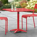 A red Lancaster Table & Seating outdoor table with chairs and drinks on a patio.