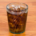 A jade GET plastic tumbler filled with ice tea on a wooden table.