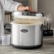 A person using an Emperor's Select large insulated rice container to prepare food in a large pot.