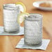 Two Fortessa Jupiter smoke gray beverage glasses with lemon slices on top of them.