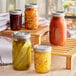 A wooden tray with Choice pint canning jars of pickles and other canned food.