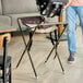 A brown assembled infant seat cradle with a metal frame and fabric seat, designed to hold an infant car seat.