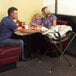 A family of four sitting at a table with a Koala Kare brown infant seat attached to the table and a baby in it.