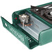 A green metal portable stove with a small brass burner.