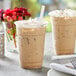 A plastic cup with a vanilla latte frappe on a table.