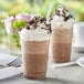 Two cups of Capora Cookies & Cream Frappe with whipped cream and cookies.