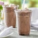 A table with two cups of Capora Cookies & Cream frappe mix drinks with straws.