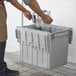 A man putting a Choice large grey chafer storage box on a shelf.