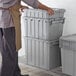 A man holding a stackable grey Choice chafer tote.