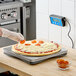 A person using an AvaWeigh pizza scale to portion a pizza on a counter.