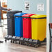 A man standing next to a Lavex 4-stream recycle station with black, blue, red, and yellow lids.