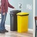 A woman standing next to a black and yellow Lavex 2-stream rectangular recycle station.