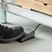 A foot stepping on a metal foot tare pedal.