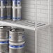 A metal Regency bottom shelf with beer kegs on it.