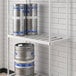 A Regency metal shelf for beer kegs with barrels and cans on it.