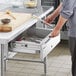 A person opening a Regency stainless steel drawer with locks.