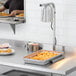 A man using an Avantco countertop heat lamp to keep food warm on a counter.