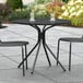 A Lancaster Table & Seating black outdoor table with chairs on a patio.