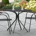 A Lancaster Table & Seating Harbor Black outdoor table on a patio with chairs.