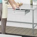 A person in a white apron using a Steelton stainless steel drawer in a kitchen.