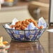 An American Metalcraft wavy sided mesh bottom basket filled with fried chicken.