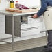 A man in a white coat using Regency stainless steel triple-stacked drawers in a kitchen.