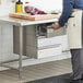 A man in a white apron opening a Regency stainless steel drawer in a kitchen.